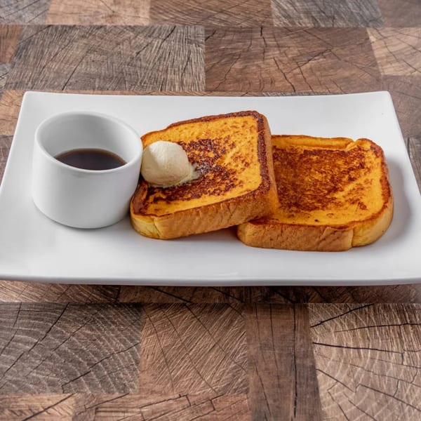 Two slices of golden French toast with a pat of butter and a side of syrup.