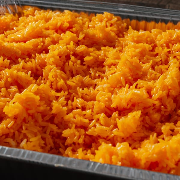 Close-up of vibrant orange Dominican rice in a foil container, ready to be served.