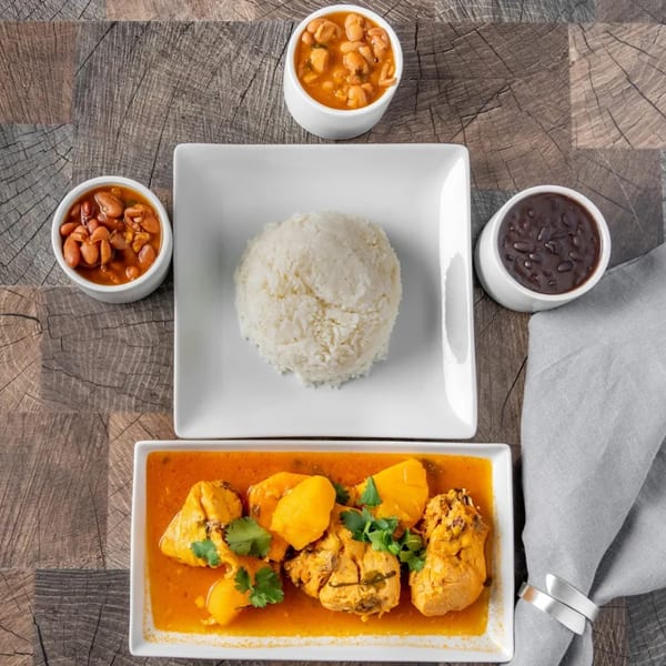 Dominican meal with chicken and potatoes in sauce, white rice, red beans, and black beans.